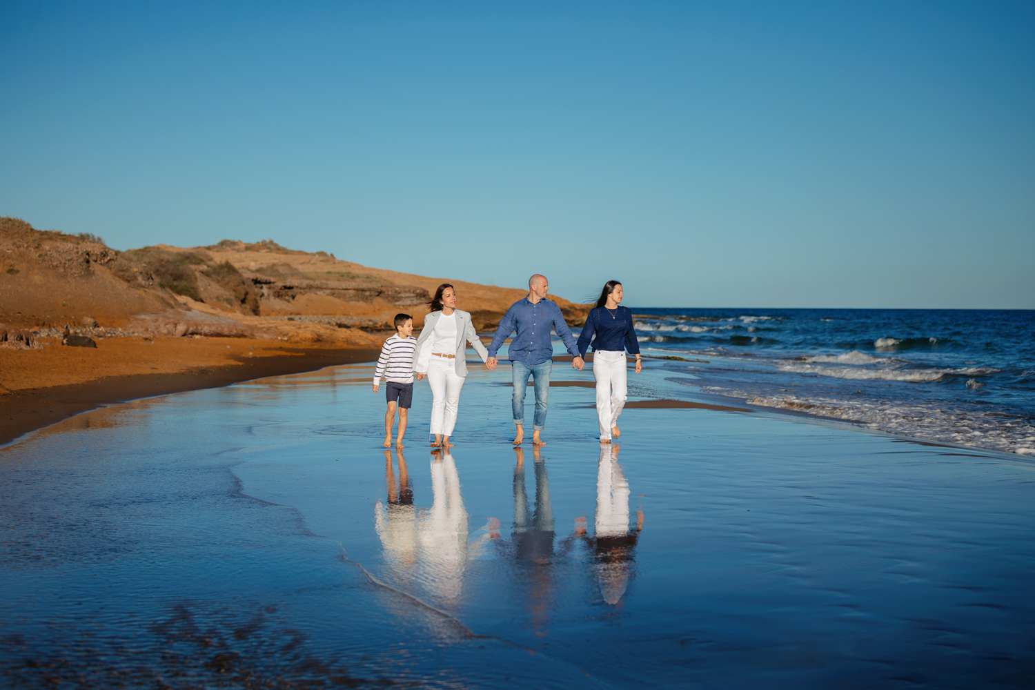 Familia paseando por la orilla de la playa